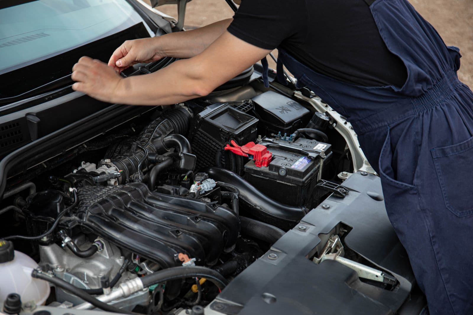 ASE-certified mobile mechanic inspecting a car's engine and battery on-site in Central Texas